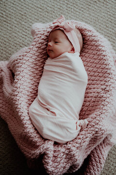 Newborn baby girl Swaddled with pink bow on head