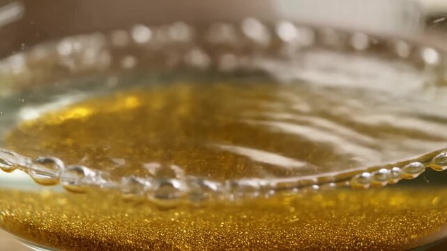 Slow motion close up tracking shot of gold glitter swirling in glass container on wooden table in kitchen during daytime