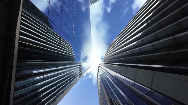 Low angle view of modern glass skyscrapers in london's financial district with sun flare, representing corporate business, economy, finance, and success in a cityscape