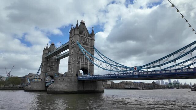 Iconic tower bridge spanning the river thames in london with the financial district skyline visible under a cloudy sky, representing the city's economy and business hub
