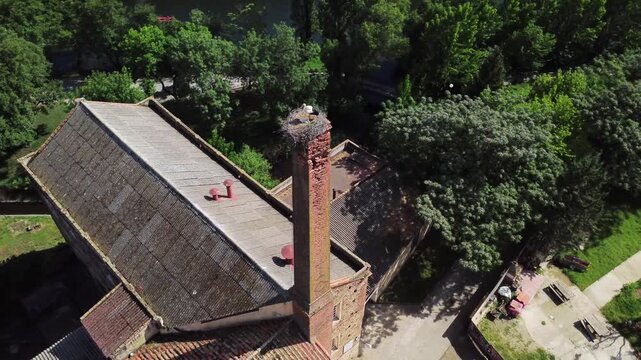 Aerial orbit around a white stork nesting on a chimney