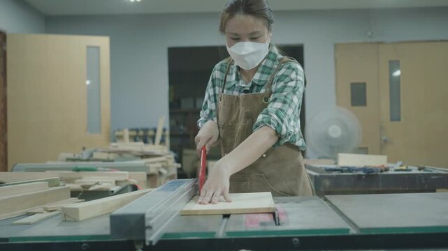 A focused individual engaged in woodworking, carefully measuring and cutting a piece of wood in a workshop environment. The scene captures the art of craftsmanship and concentration required in wood p