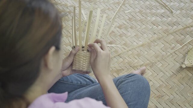 A focused individual skillfully weaves natural materials, showcasing traditional craftsmanship. This image captures the artistry and patience of handwork, highlighting the beauty of creating something