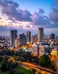 Fototapeta premium Aerial view of a city skyline at dusk with lit buildings