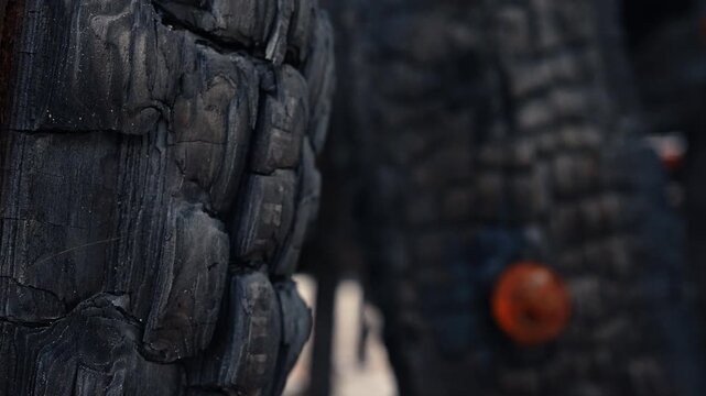 Macro texture of charred burnt wood after building fire disaster. Close up shot of black charred wood surface with alligatoring texture from high heat exposure.
