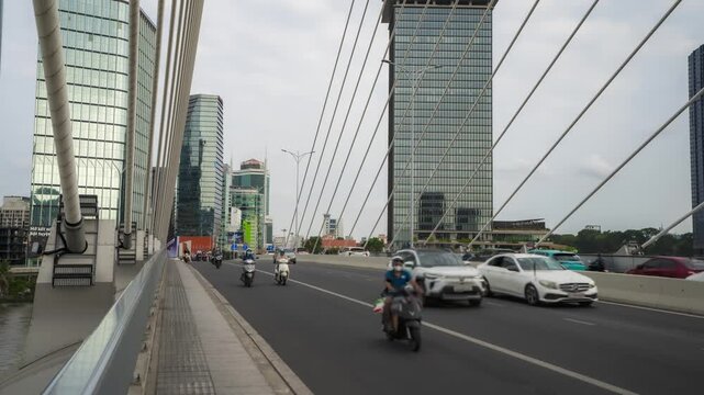 Daily traffic on Ba Son Bridge in Ho Chi Minh City with modern city skyline, Vietnam. High-angle urban timelapse.