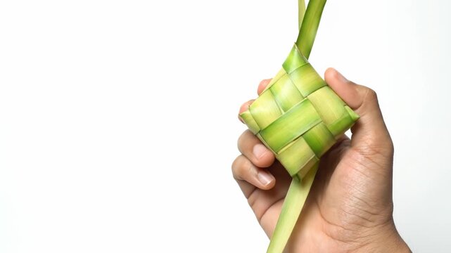 Ketupat Ramadan Eid. Hand Holding Traditional Woven Palm Leaf Rice Dumpling on White Background