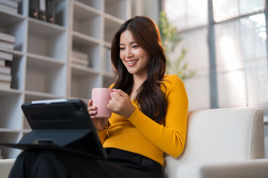 Young woman smiling, watching tablet, enjoying coffee break