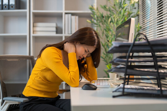 Young woman experiencing neck pain at office desk