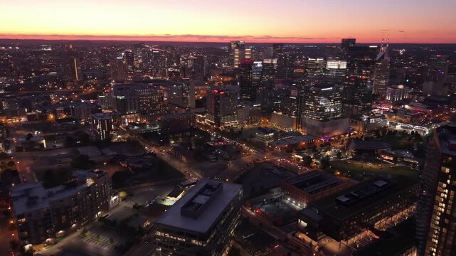 Aerial orbit over downtown Nashville capturing glowing skyline and riverfront during sunset transition