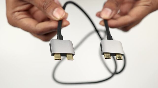 Dual USB Type C Cable in Hands with Connectors Facing to Camera Isolated on White Background for Fast Charging Laptop Connection and Digital Technology Use.
