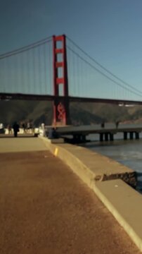 Vertical video: Panning camera showing red tower shifting left at harbor with pier, people in coats