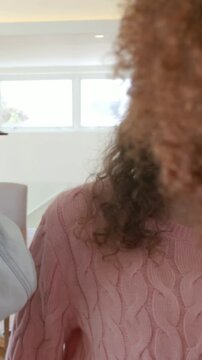 Vertical video: Pulling back denim jacket woman chatting with pink sweater friend dining by window