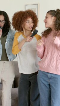 Vertical video: Singing friends with left singer starting song at home for fun, sharing mics