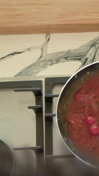 Vertical video: Stirring cook mixing sauce in pan, shifting stirring pasta at stove avoiding clumps