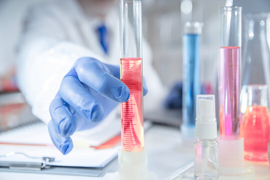 Gloved hands handling pharmaceutical samples results in lab, drug testing and quality control with chemical glassware and solutions.