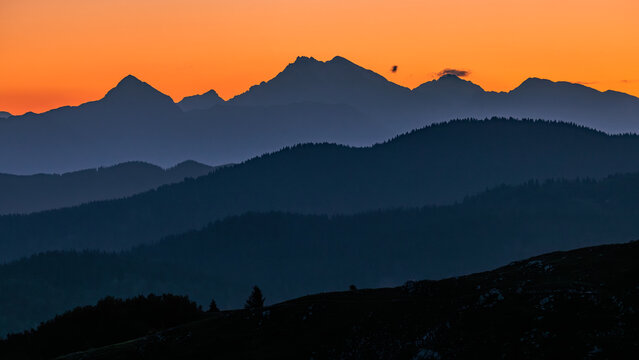 View of layered mountain silhouettes under a vivid orange sunset sky Sorica, Skofja Loka, Slovenia.