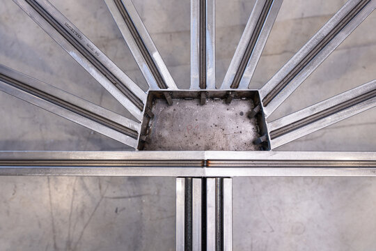 Vue plongeante d'un assemblage radial de profil&eacute;s en aluminium rainur&eacute;s convergeant vers un moyeu central, illustrant une structure g&eacute;om&eacute;trique pr&eacute;cise pour l'ing&eacute;nierie modulaire.