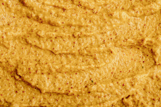 Mustard sauce with grains close-up. Hot spices as a background. Texture of Dijon mustard.