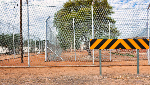 High Security Chain Link Fence with Barbed Wire and Warning Sign restricted access.