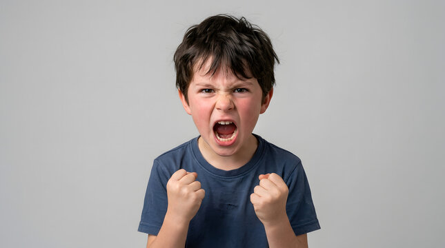 Young boy with his arms clenched and mouth open, expressing intense anger and frustration in a studio portrait