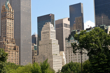Obraz premium City Skyline Showcased. Green Trees Accentuate Manhattan Skyline At Midday Times new york