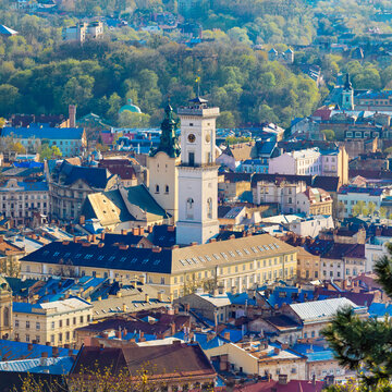 Aerial view of Lviv old town with Town Hall tower and historic architecture. Sunset in Lviv Ukraine illuminates colorful buildings, ancient churches and central square under warm evening light