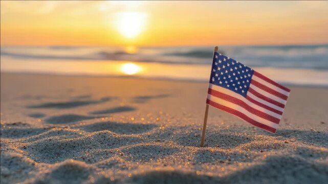 An American flag flying on a beach with the ocean behind it. The sun is setting, creating a beautiful golden glow over the scene. This captures a sense of patriotism