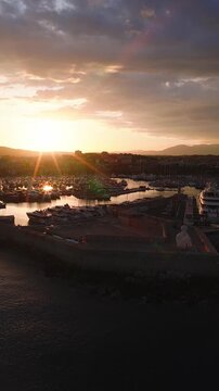 Aerial view of Port Vauban, Antibes, with yachts and superyachts near Fort Carre and Le Nomade. The sun sets with starburst flares as a drone glides above piers.