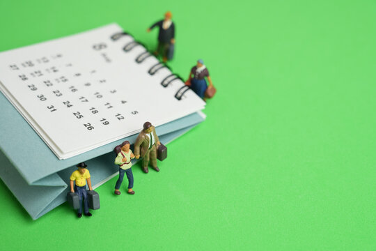 close up of calendar and miniature figures on the green table background, planning for business meeting or travel planning concept
