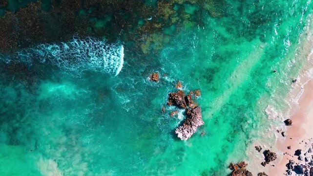 Aerial view showing the waves crashing against the sandy reefs of the beach