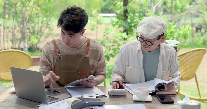 Asian father coaches son beside laptop, tablet, receipt printer, report sheet, coffee cup, teaching cafe order management, cashless payment planning, family business workflow lesson and care.