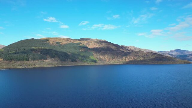 Aerial View of Calm Water of Massive Lake at Balmaha Valley Village Near Glasgow Landscape During Sunset. Village is a popular tourist destination for picnickers and day trippers from Glasgow