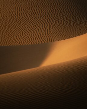 View of rippled sand dunes with golden light and deep shadows in the desert of Balochistan, Pakistan.