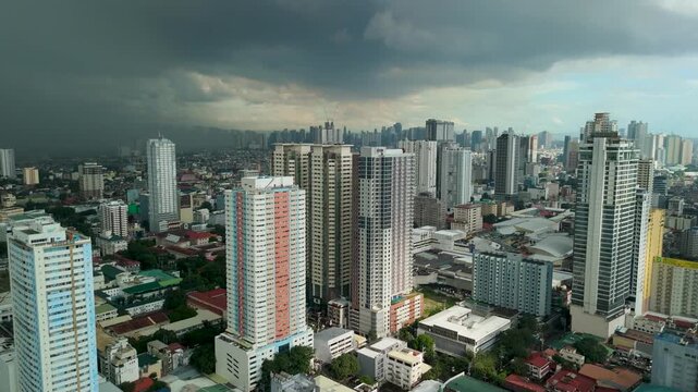 Drone shot of the Manila metropolitan skyline with buildings under dramatic gray rain clouds during the monsoon season in the Philippines