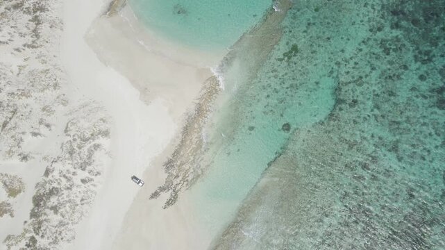 4WD Parked on White Sand Beach Near Coral Reef, Turquoise Water and Remote Tropical Coastline in Australia - Top Down Aerial Drone Shot