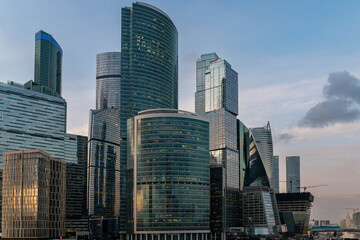 Fototapeta premium Modern Glass Skyscrapers At Dusk Reflecting Golden Sunset, Curved Mirrored Towers And Corporate Highrises In Moscow International Business District,