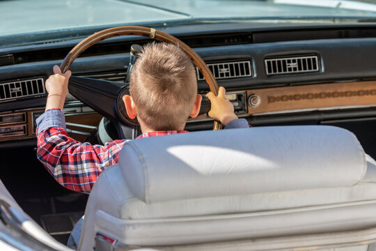 Funny image with one little boy at the wheel of an old and vintage car.