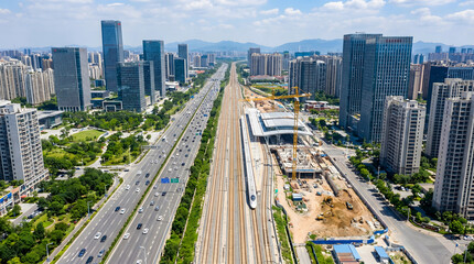 Naklejka premium High-speed train passing through a modern urban landscape with skyscrapers and busy traffic arteries