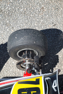 View of a worn slick racing tire and brake disc assembly of a go-kart on an asphalt track.