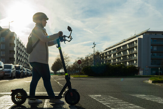Woman with helmet using electric scooter in city