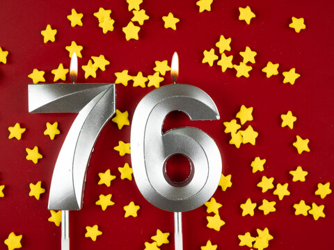 Number 76 silver celebration birthday candle on red with golden stars background. Seventy-six years birthday. celebrating anniversary and birthday