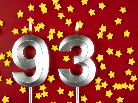Number 93 silver celebration birthday candle on red with golden stars background. Ninety-three years birthday. celebrating anniversary and birthday