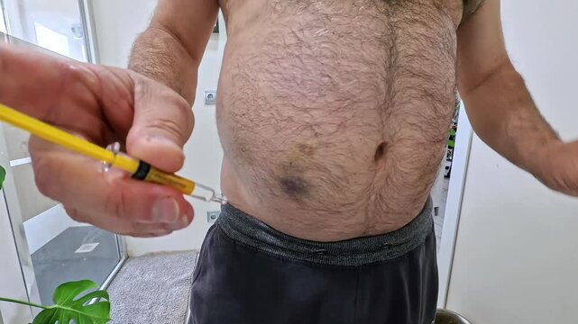 A close-up, first-person perspective video of a man self-administering a medication injection into his abdominal area. The footage shows the preparation of the syringe, the pinching of the skin, and t