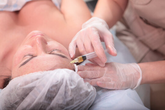 Plasmolifting procedure. Cosmetologist makes injections of plasmolifting. Blood in test tube. Close-up of patient's face is out of focus. Concept of cosmetology. Selective focus.