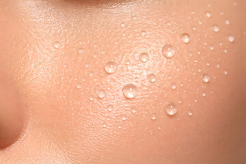 Fototapeta premium Extreme macro of radiant human skin with fresh water droplets. Concept of hydration, skincare, moisture, and natural beauty texture with visible pores.