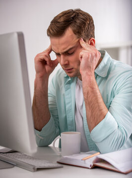 Man with headache at computer.
