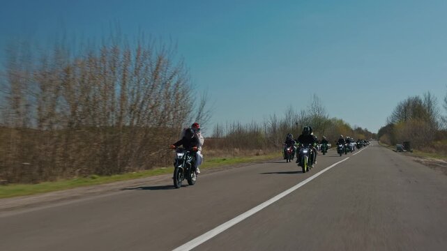 Group of bikers riding on a sunny country road, slow motion