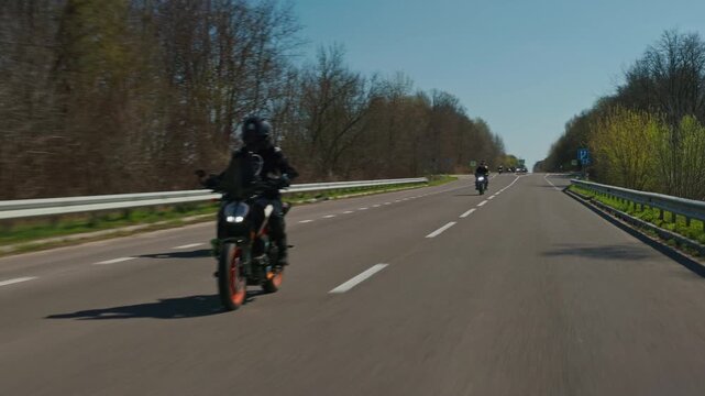 Group of bikers riding on a sunny country road, slow motion