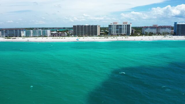 Aerial view capturing turquoise waters meeting a stretch of beachfront residences. Suitable for travel promotions or real estate showcases.